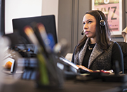 A woman at a computer wearing a headset.