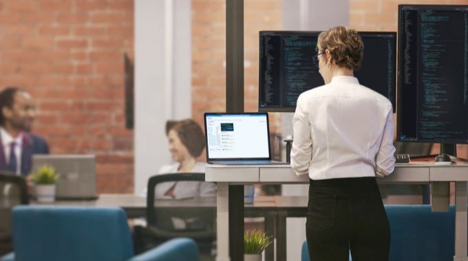 Developer in focused work; standing desk in context of FinTech. Investment advisor reviews real-time data in an intelligent app powered by Azure to assist with customer investment decisions.