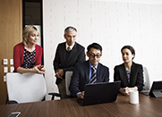 Group of four business people look at a laptop screen