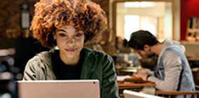 Woman facing camera looks down at her laptop