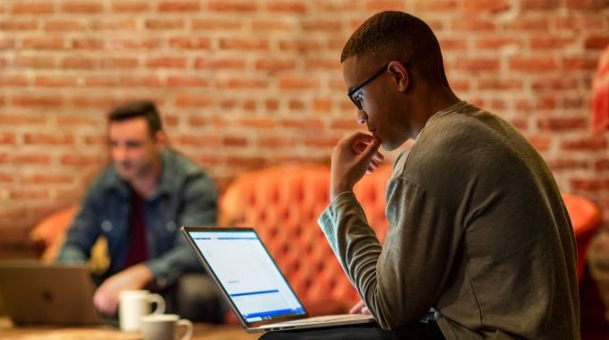 Real people. Male developers work remotely from a café.