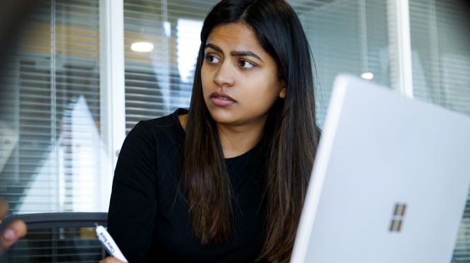 Woman sitting in front of opened laptop taking notes