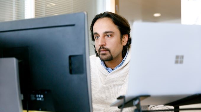 Man sitting at desk looking at his two computer monitors