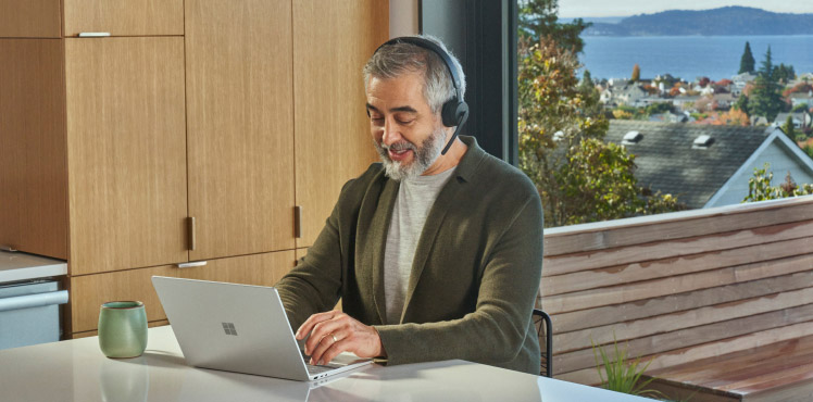 A professional with a headset works on a laptop.