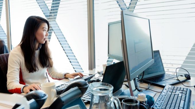 Woman sitting at desk working on her computer monitor