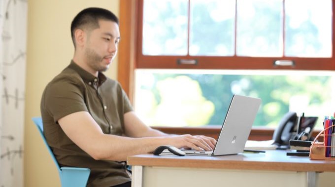 Man sitting at desk using a Surface laptop